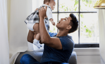 dad lifts baby by sunlit window