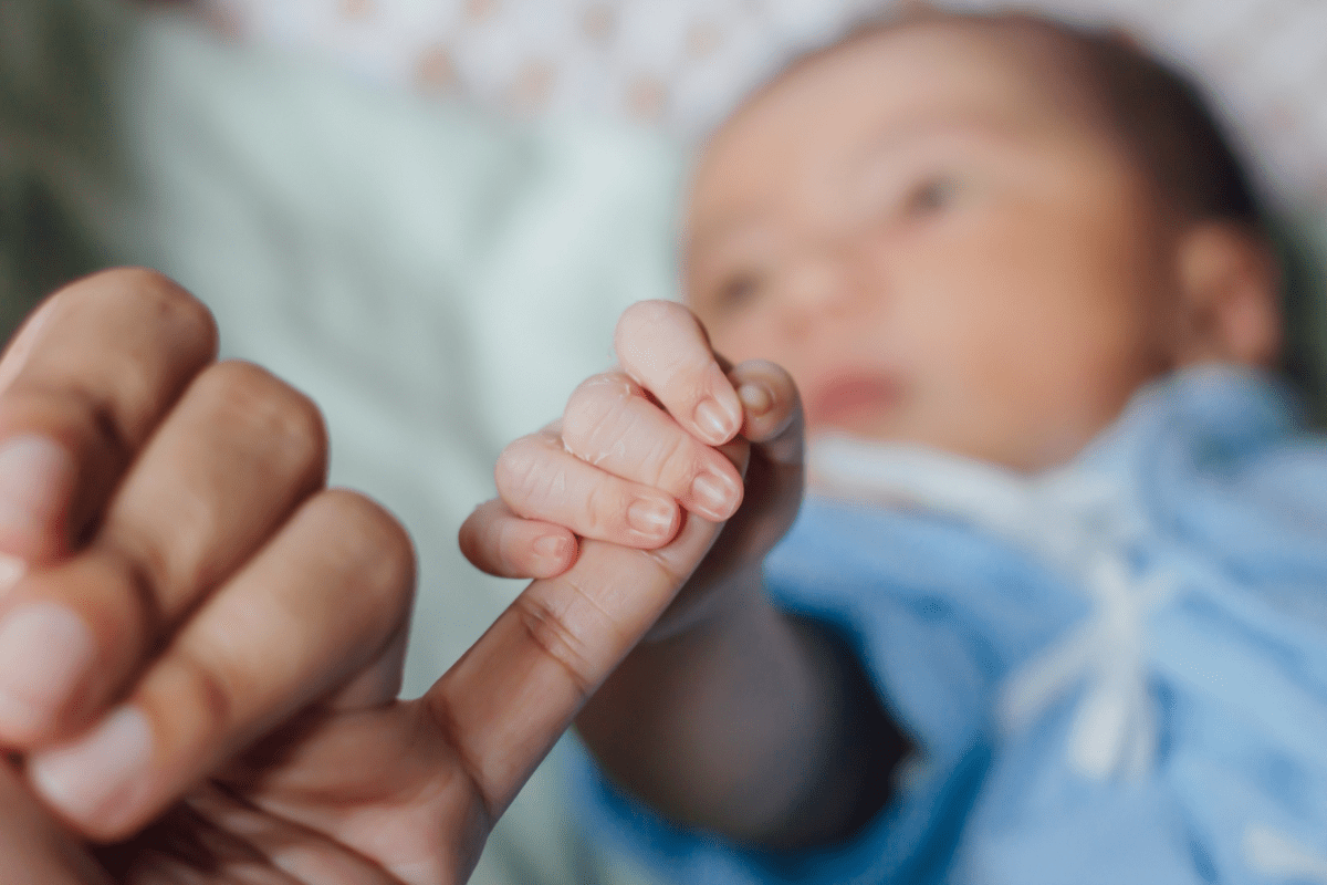 baby holds adult's pinky finger