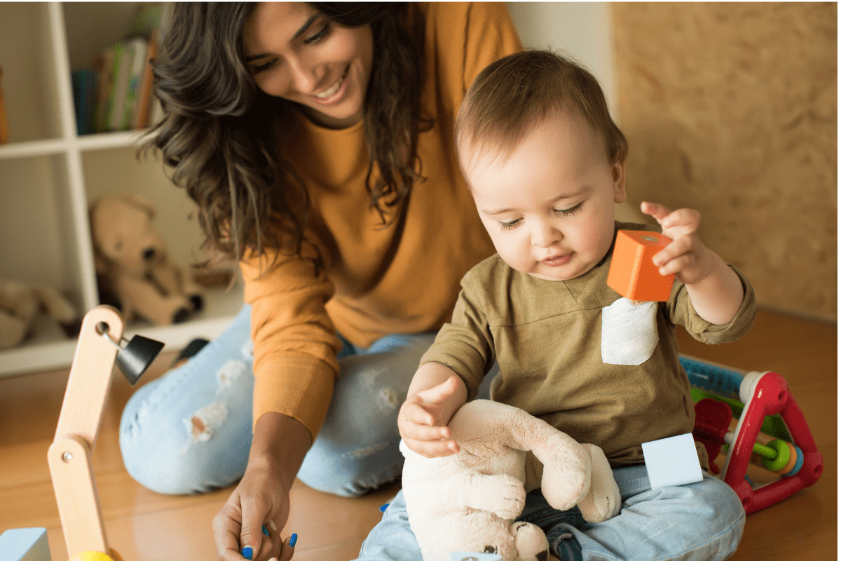 mom watches baby play with blocks