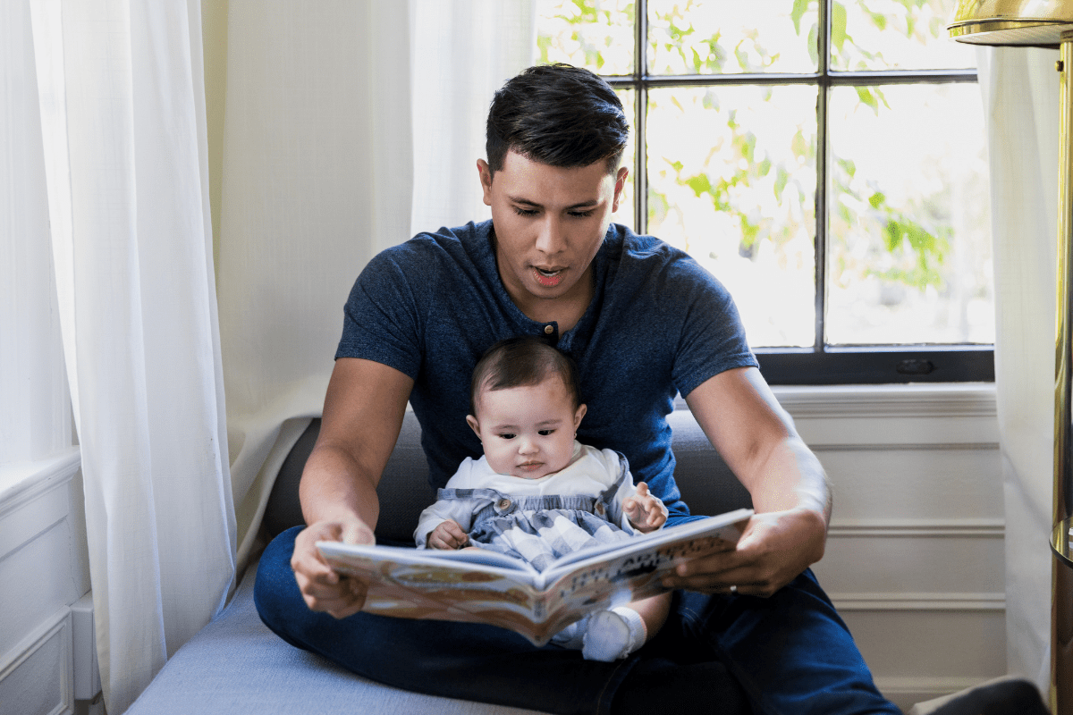 dad reads book to baby in lap