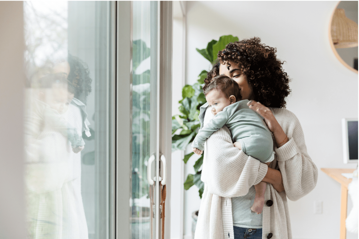 mom holds baby by window