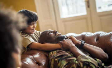 son holds military dad's neck on couch