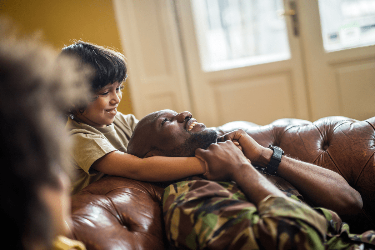 son holds military dad's neck on couch