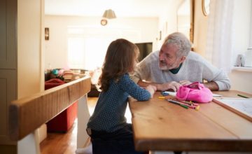 older man talks to young child at table