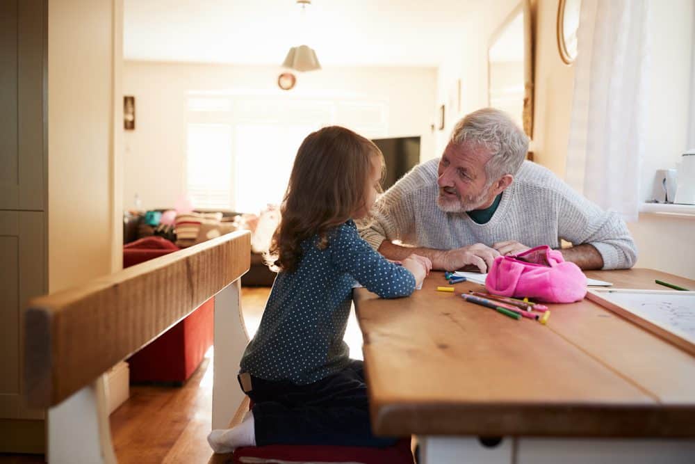 older man talks to young child at table