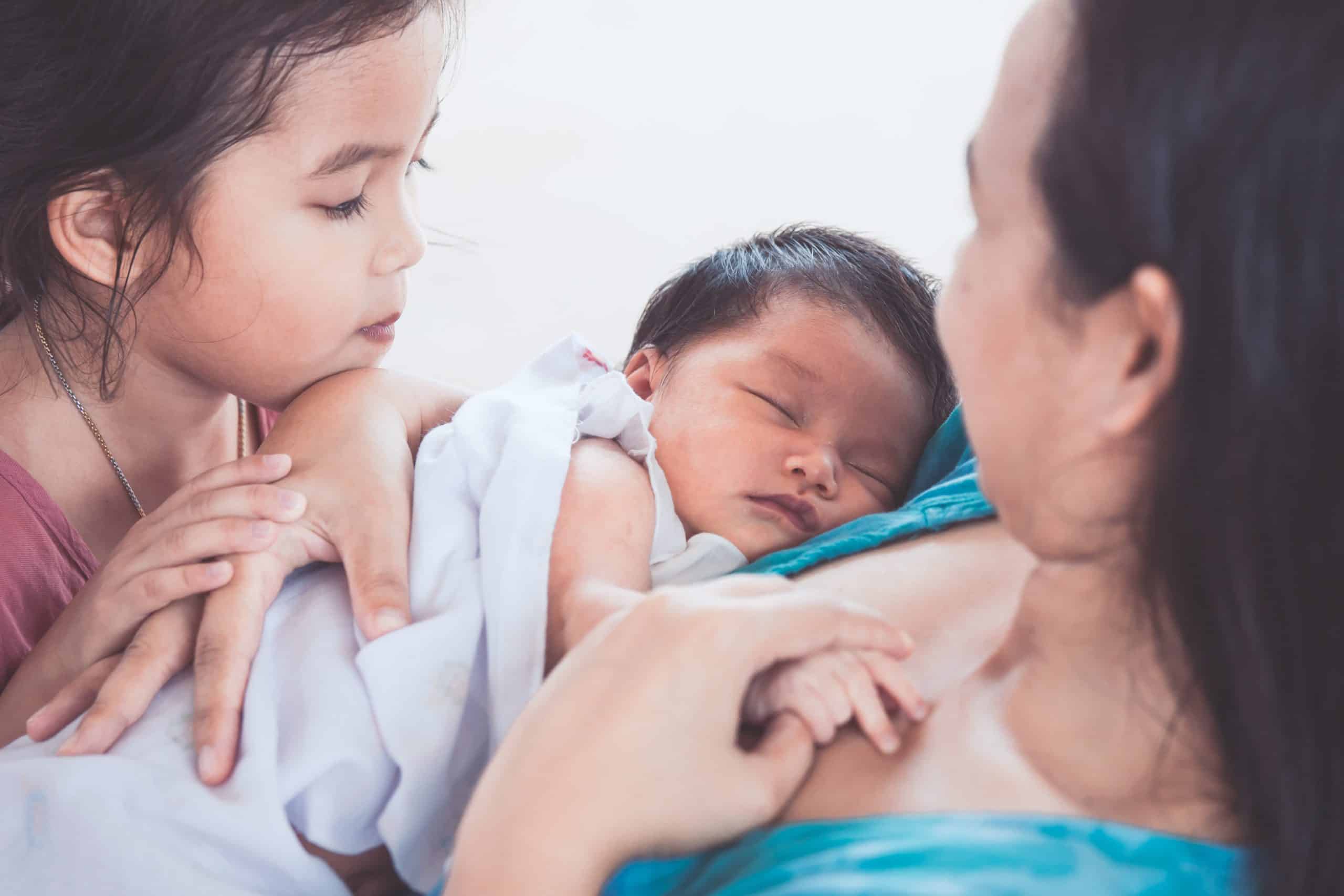 Baby Sleeping in mother's arms with sister watching