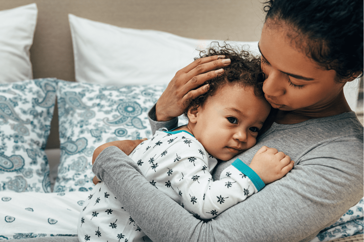 mom in grey shirt comforts scared baby