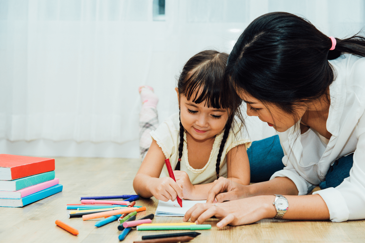 mom and daughter color with pencils on floor