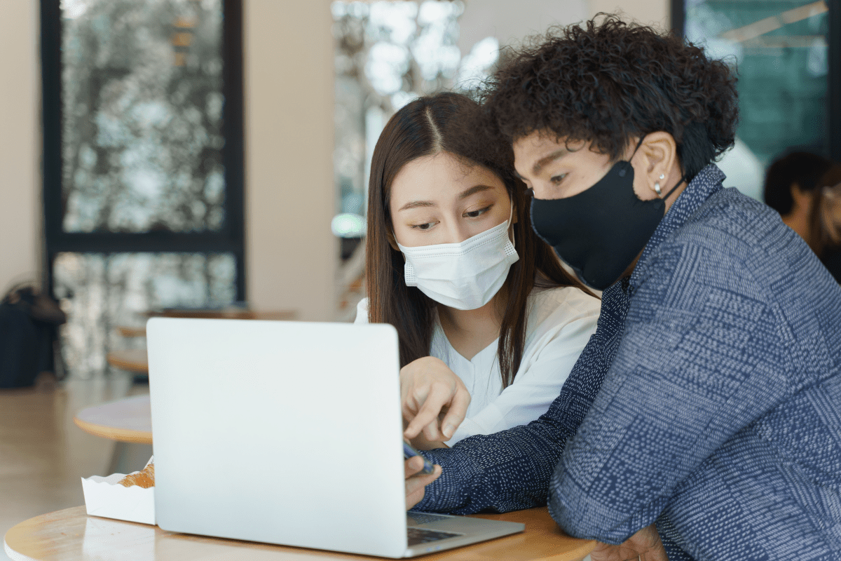 two people wearing masks looking at laptop