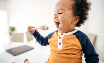 toddler feeds self with a spoon