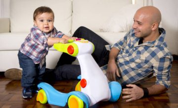 dad smiles at baby boy pushing toy