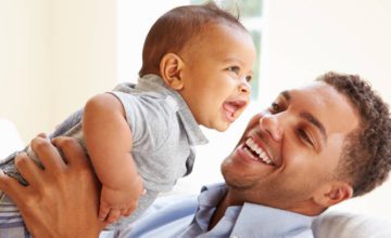 father smiling and holding laughing baby