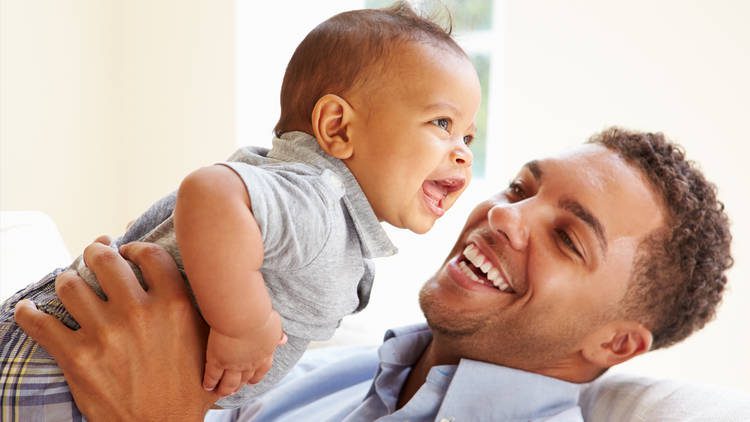 father smiling and holding laughing baby