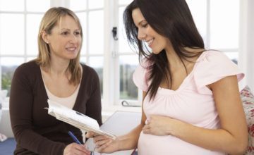 pregnant woman reading book and talking to other woman