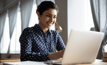 woman smiling at laptop sunlit window