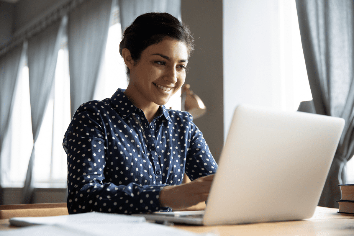 woman smiling at laptop sunlit window