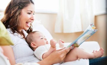 Caregiver with infant on her lap reading a book