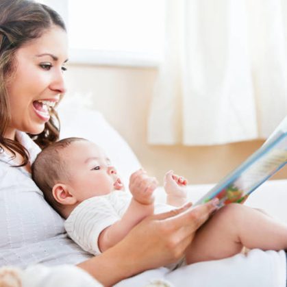 Caregiver with infant on her lap reading a book