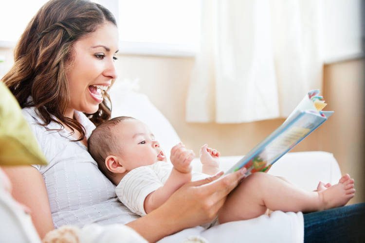 Caregiver with infant on her lap reading a book