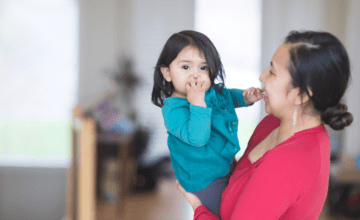 mom wearing red holds child wearing blue