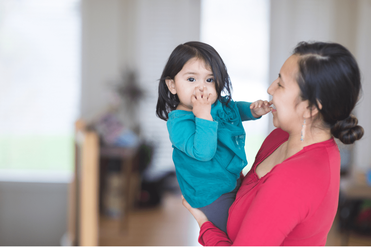 mom wearing red holds child wearing blue