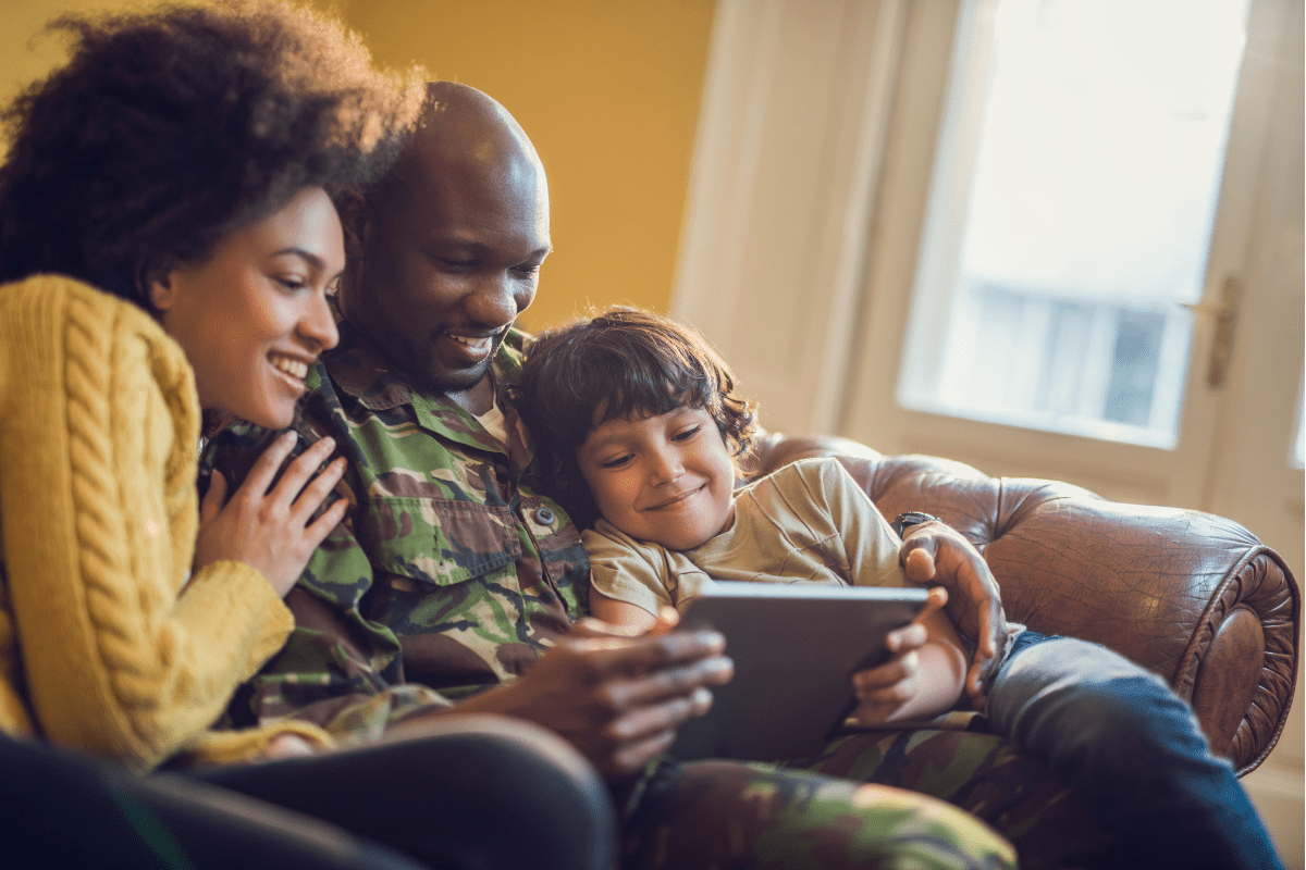 military dad with wife and son on couch with tablet