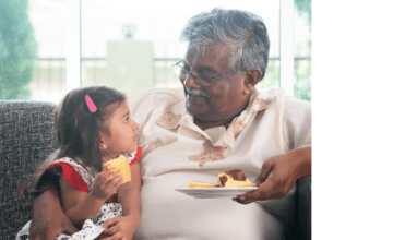 grandpa gives granddaughter food on couch