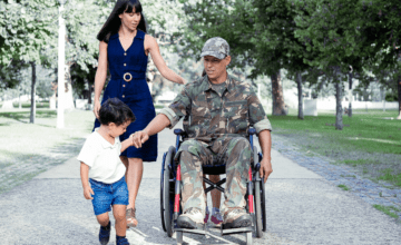 veteran dad in wheelchair holds son's hand