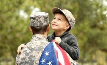 military dad with son carrying American flag