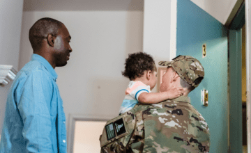 military mom holds baby next to husband in blue