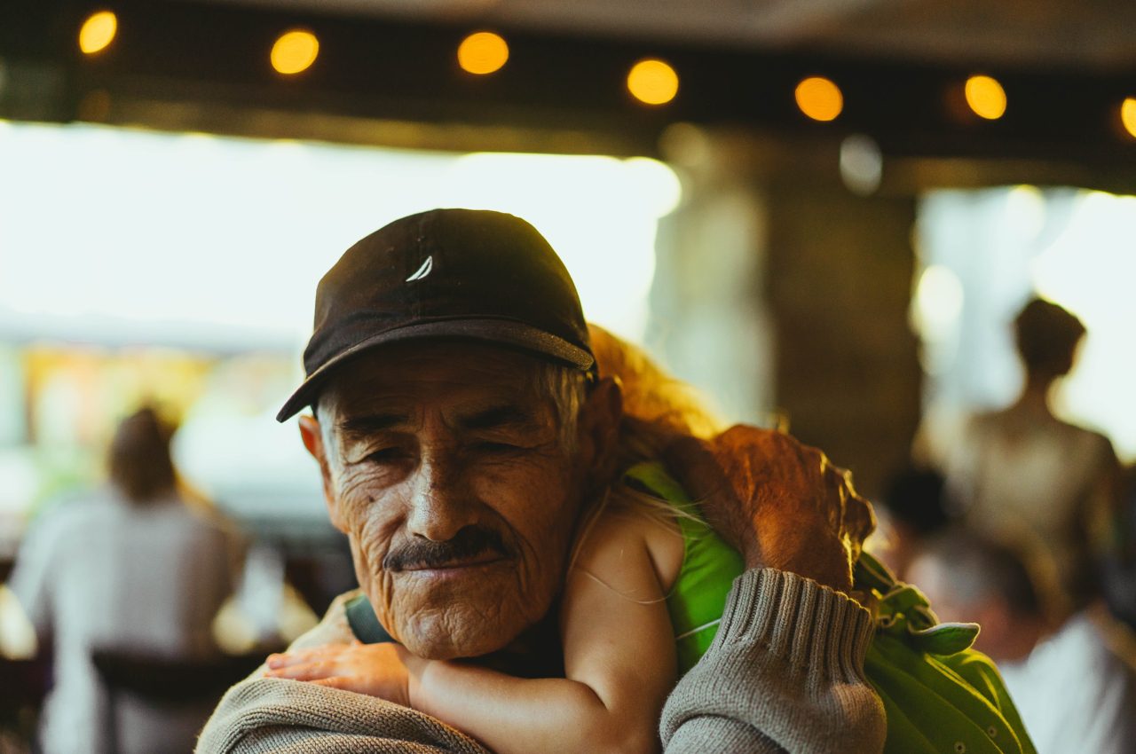 grandpa wearing black cap holds child