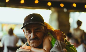 grandpa wearing black cap holds child