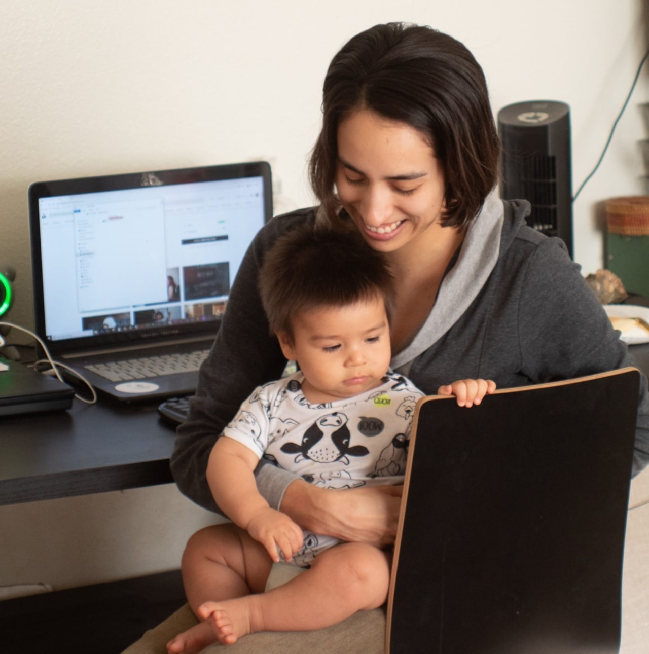 mom holds baby on lap at desk laptop