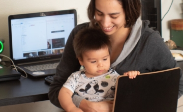 mom holds baby on lap at desk laptop