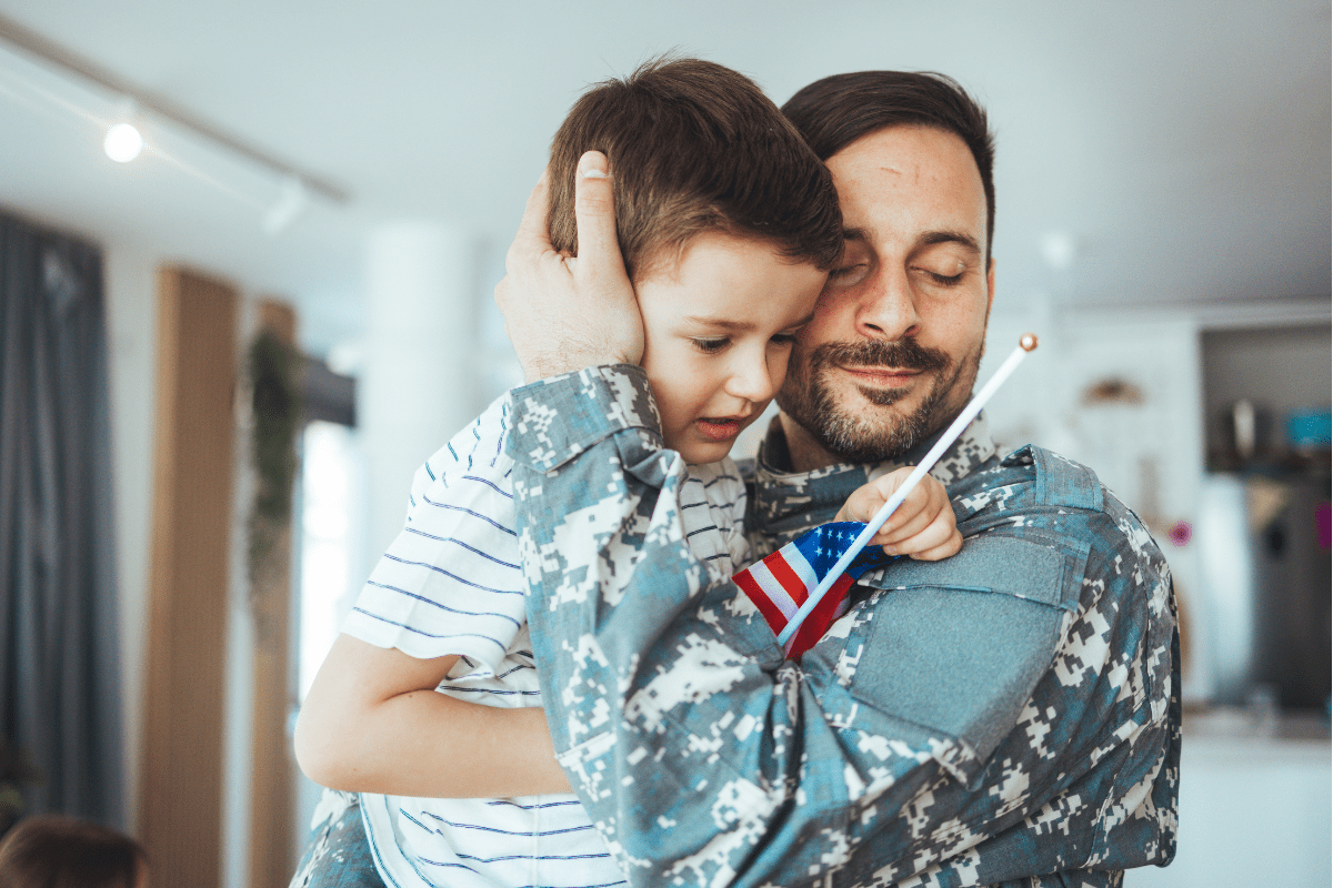 military dad embraces son holding flag