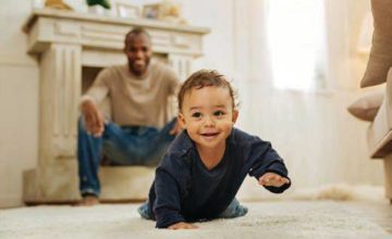 Baby learning to crawl with dad