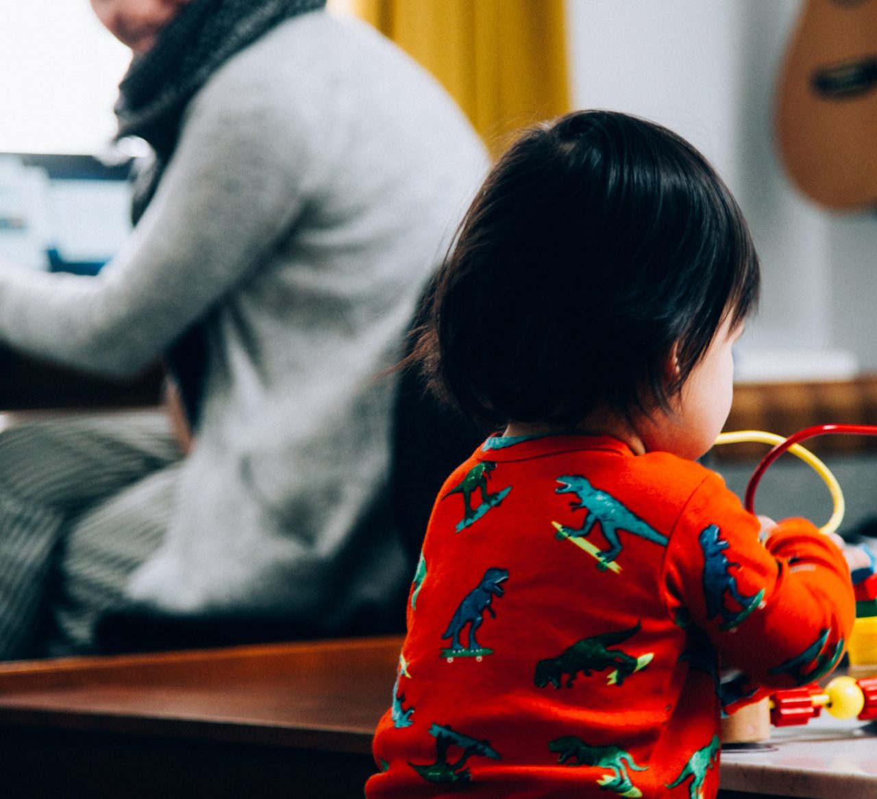 child plays alone with parent on laptop