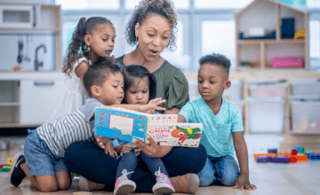 woman reads book to four children