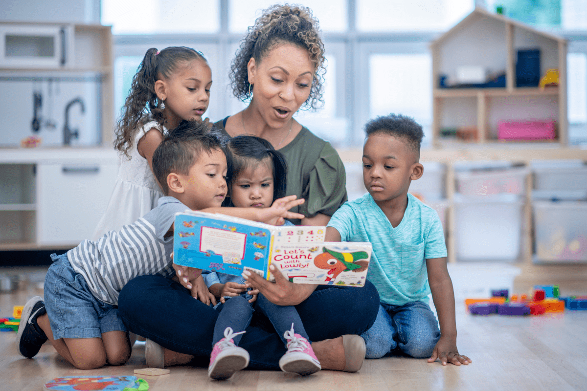 woman reads book to four children