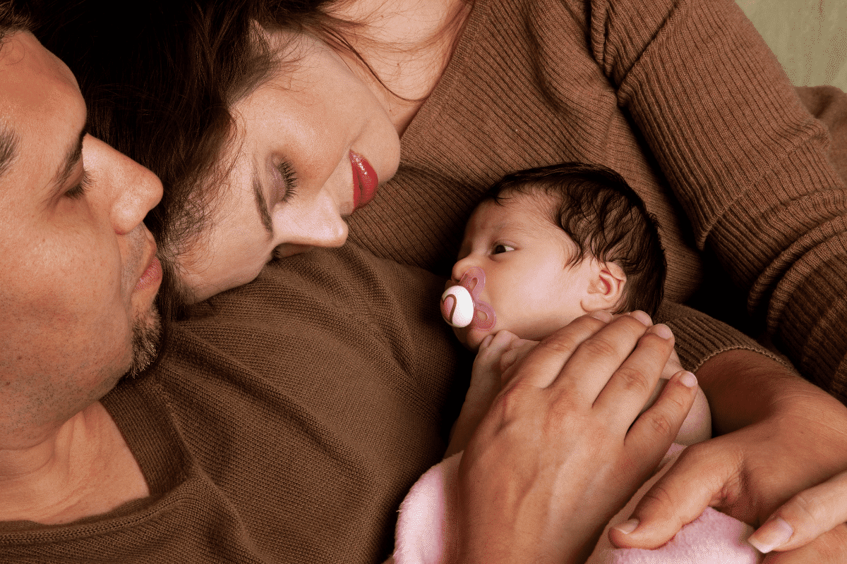 parents wearing brown hold newborn