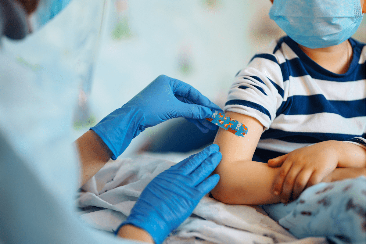 kid wearing mask gets a bandaid from doctor