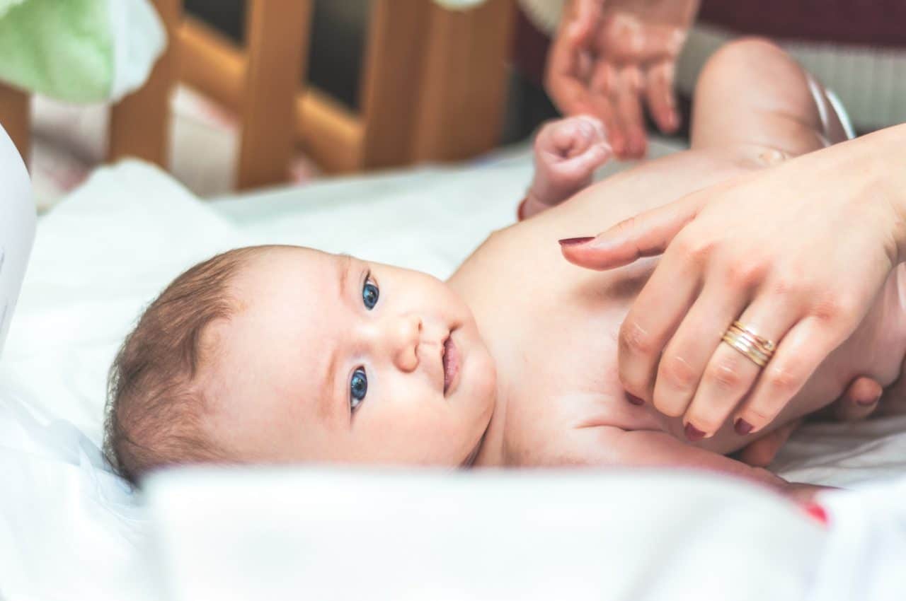 mother's hands pick up baby in crib