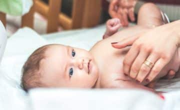 mother's hands pick up baby in crib