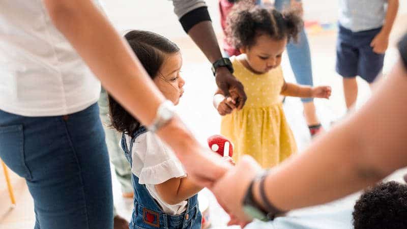 adults and toddlers holding hands