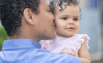 father kissing daughter in pink dress