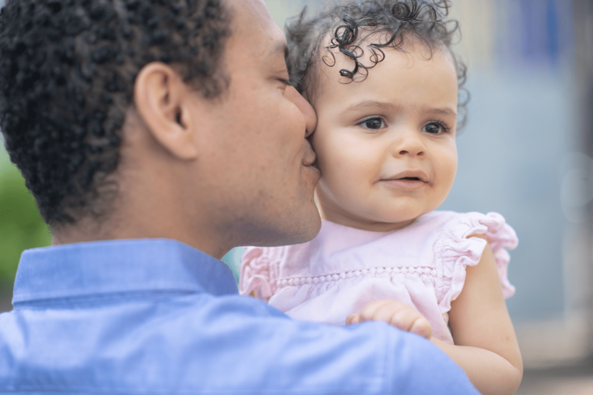 father kissing daughter in pink dress