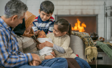 family gazes at baby on couch with fireplace