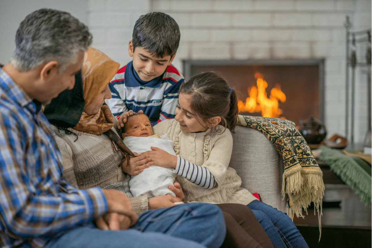 family gazes at baby on couch with fireplace
