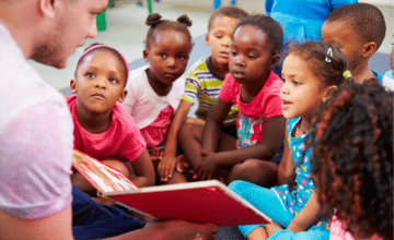 Man reads book to group of children