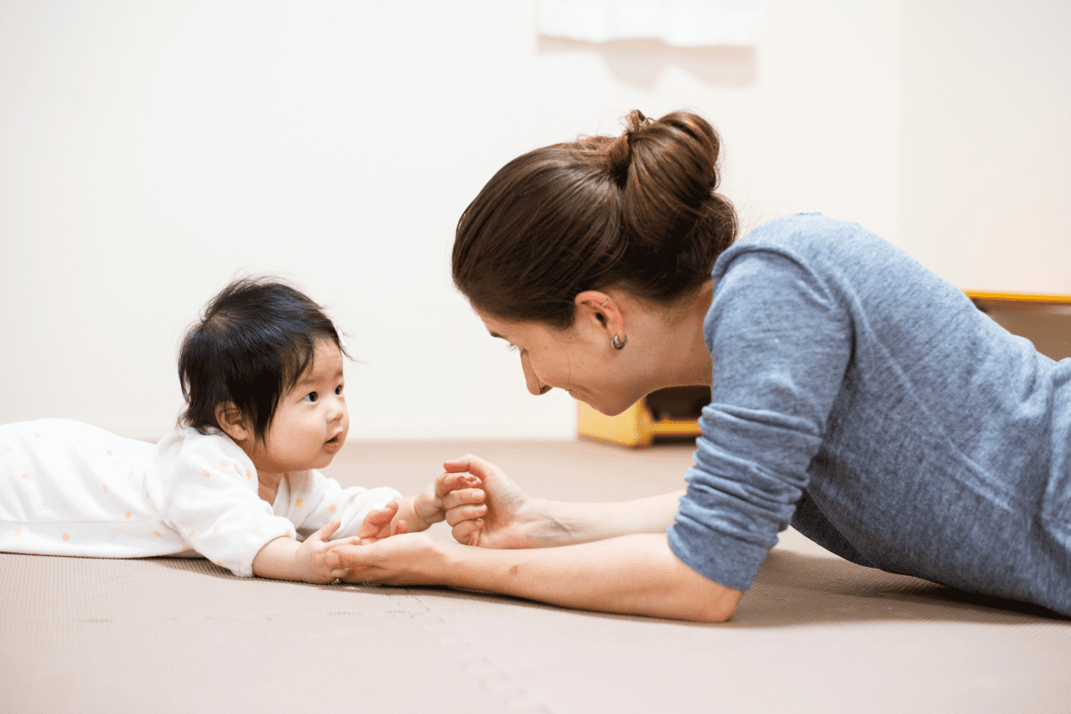 baby and caregiver lying on their bellies